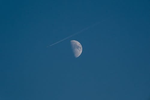 An Airplane Passing the Moon in the Sky 