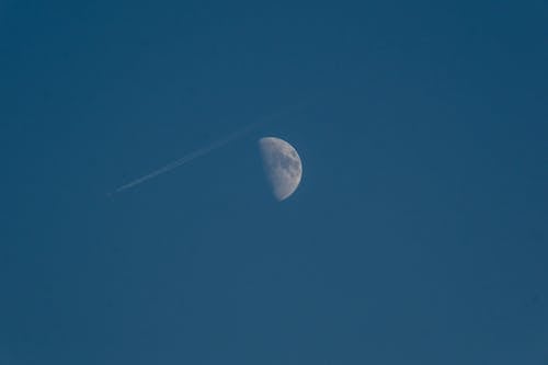View of Half Moon and an Airplane against Clear Blue Sky 