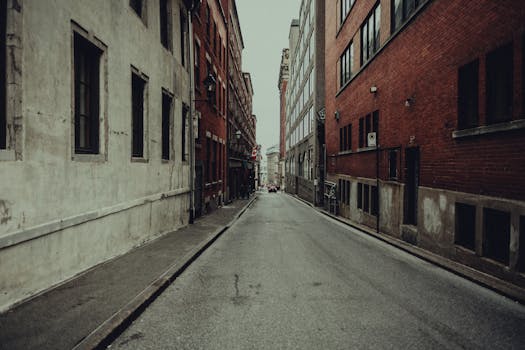 Explore an empty urban street lined with vintage buildings and brick facades under an overcast sky.
