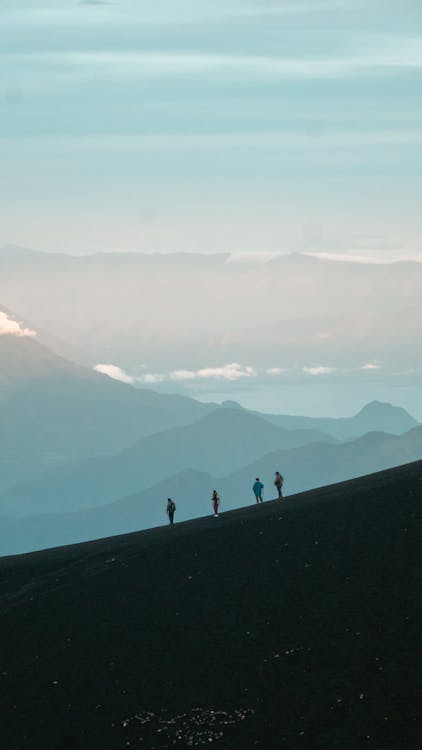 Silhouettes of People on the Slope of the Hill