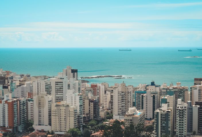 High angle view of a modern coastal city with skyscrapers and ocean backdrop.