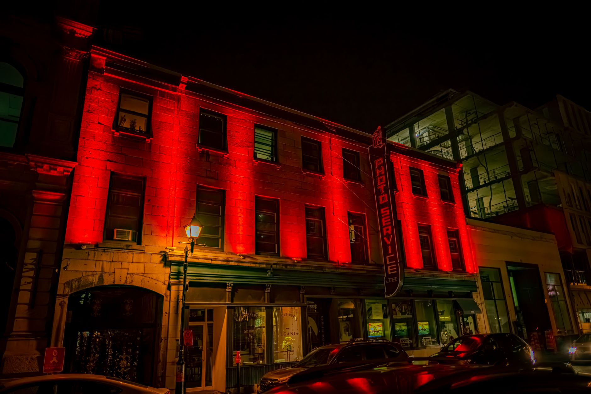Illuminated urban building facade with red neon lights at night, capturing vibrant city life.