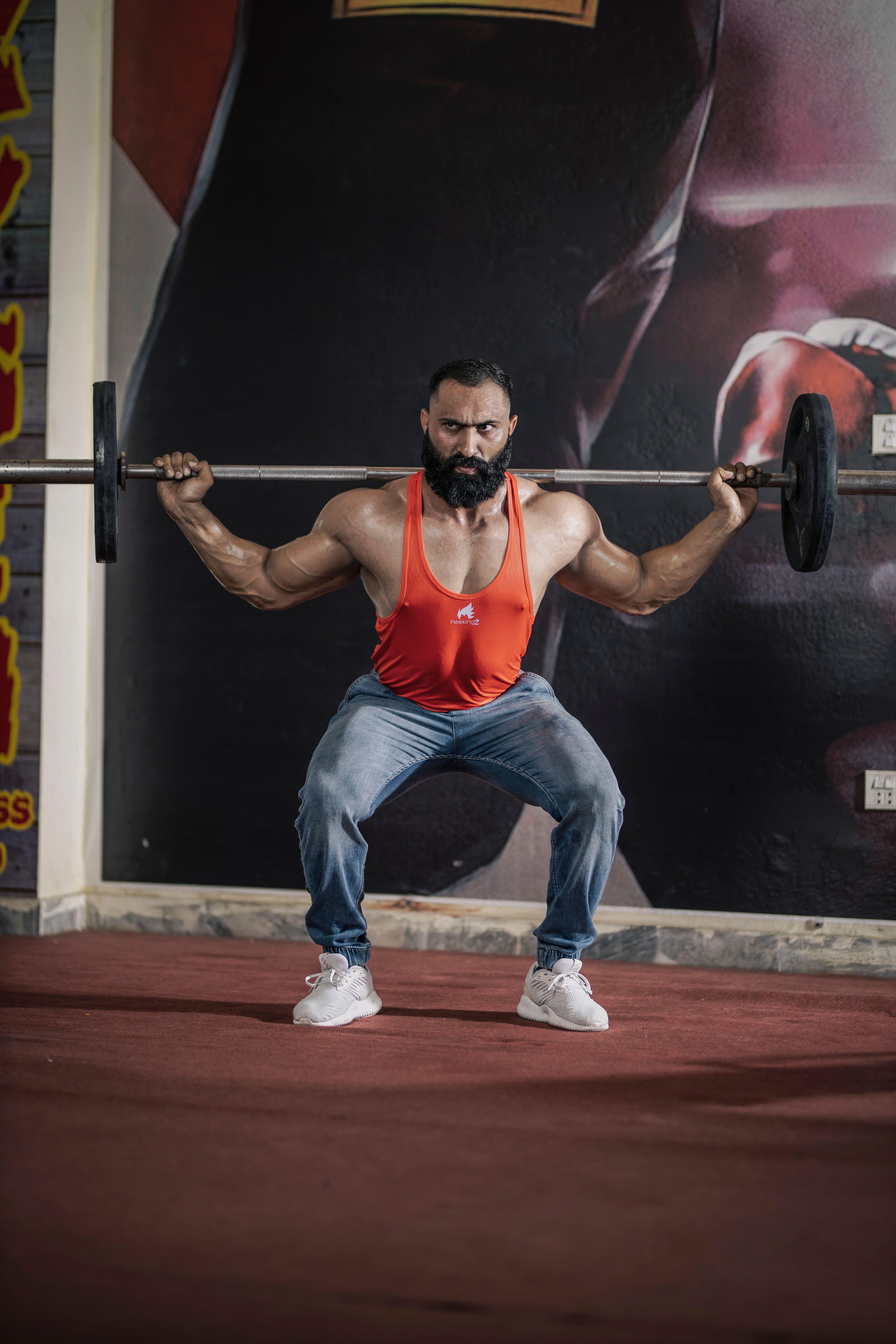 Athlete performing a heavy barbell squat under coach supervision