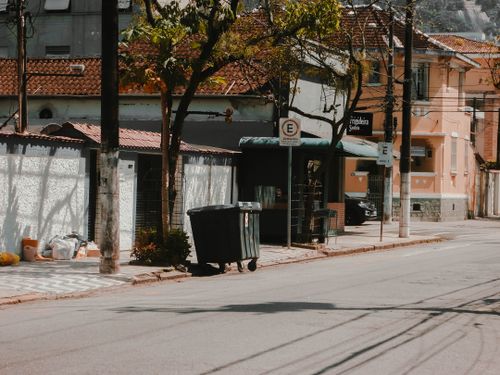 Free Serene urban street with trees, sidewalk and trash bin, capturing city life. Stock Photo