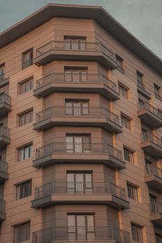 Stylish modern apartment building exterior with multiple balconies under warm light.