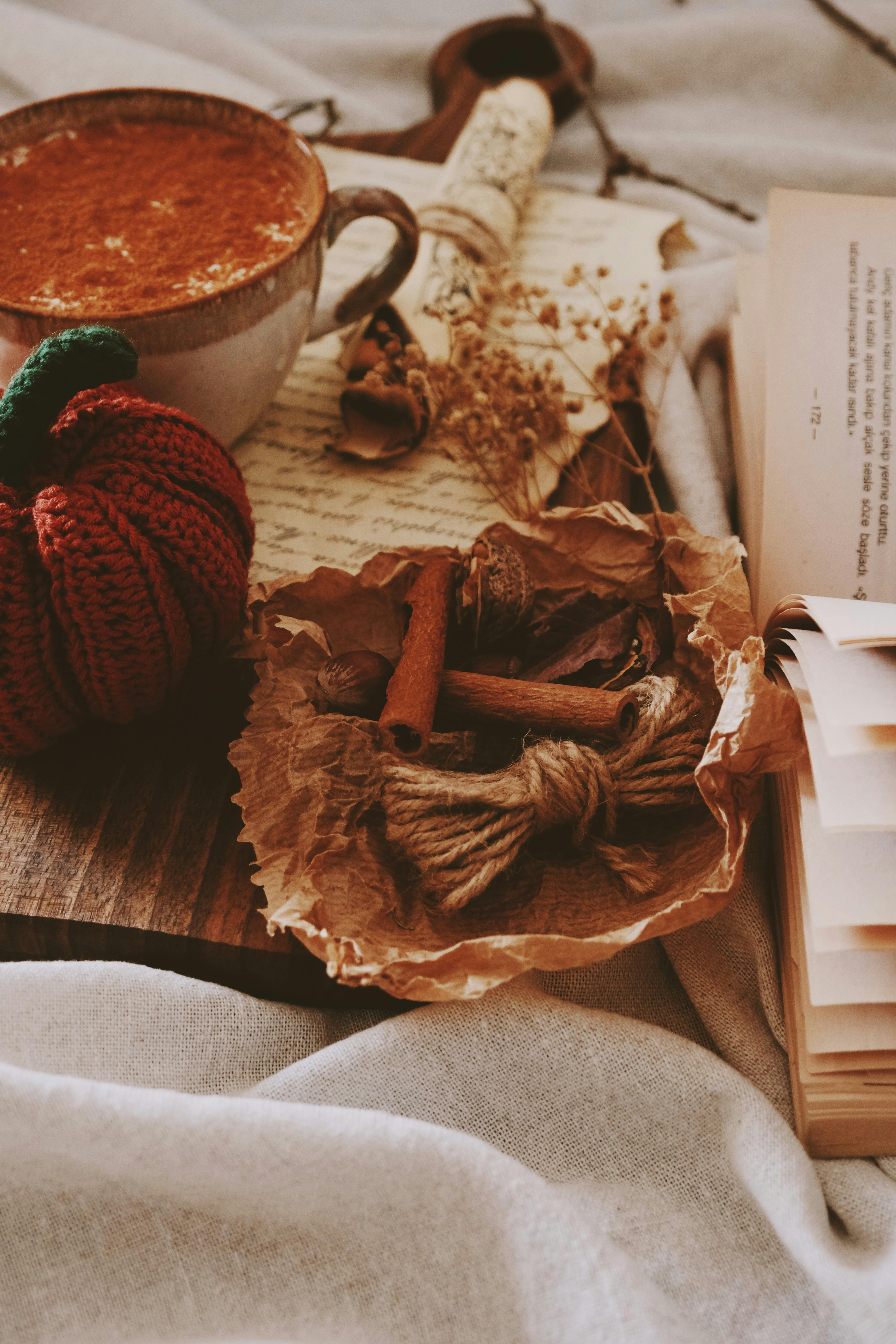 Warm autumn setup with coffee, cinnamon sticks, and dried flowers on a cozy background.