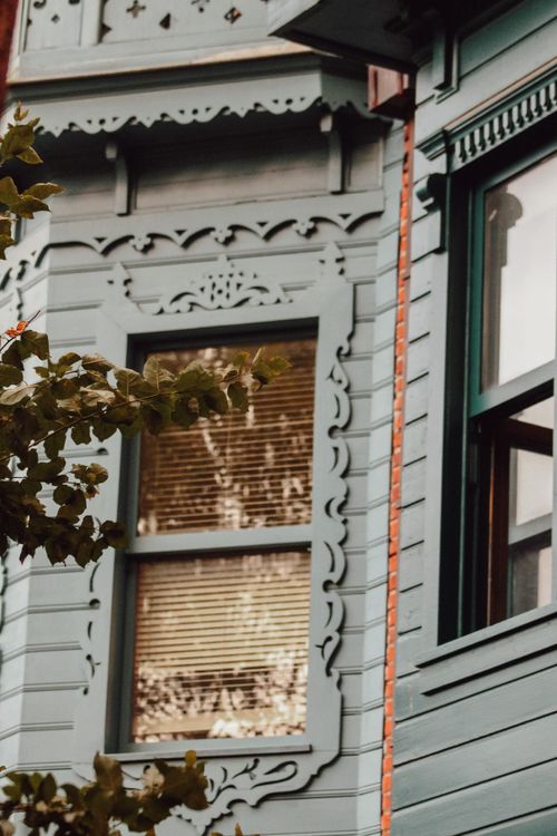 Free Close-up of a Victorian house facade showcasing intricate window designs and ornate trim. Stock Photo
