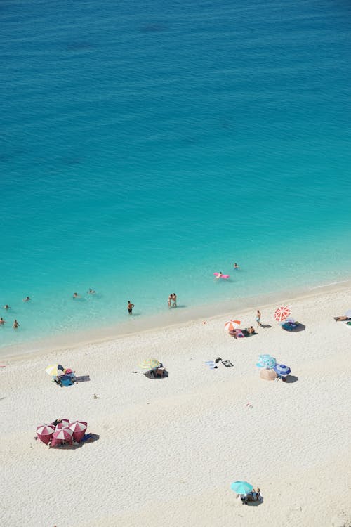 Aerial View of People Sunbathing on a Beach and Swimming in Turquoise Water 