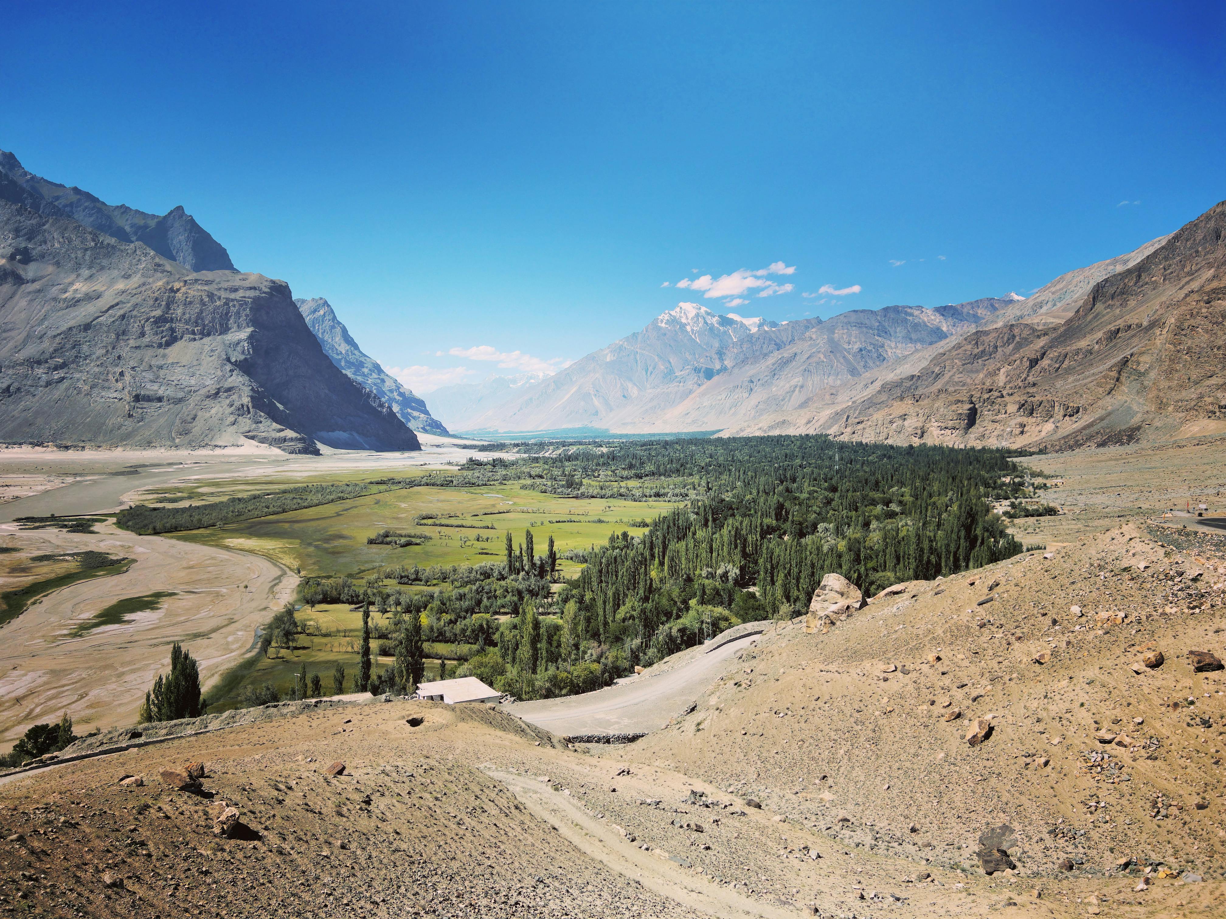 Aerial view of a lush oasis nestled among dry mountains in a scenic valley.