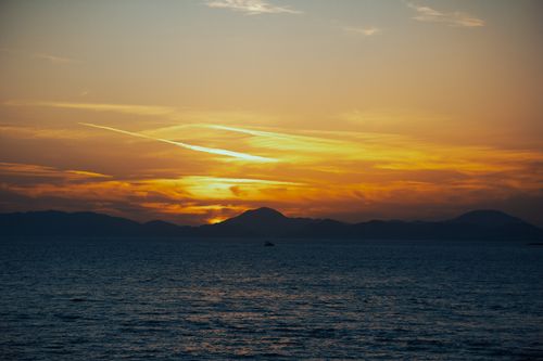 Free Dramatic ocean view with sunset over mountains, perfect for travel inspiration. Stock Photo