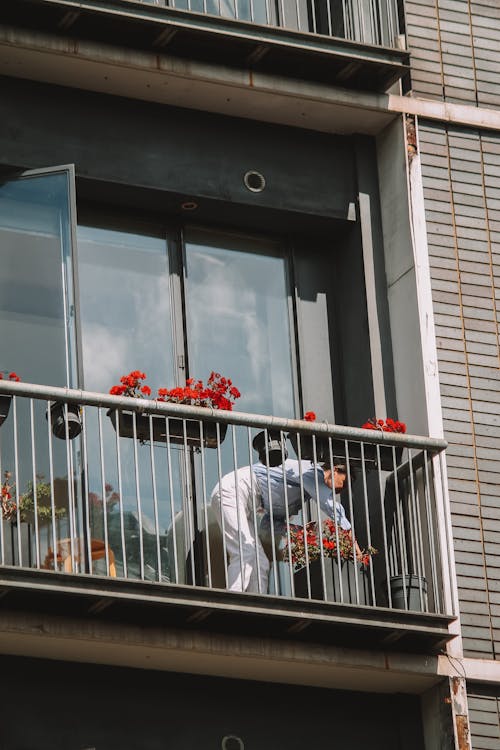 Woman Watering Plants on a Balcony