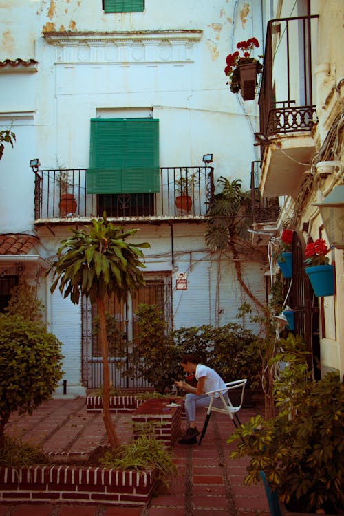 Woman Sitting on Chair near Building Walls