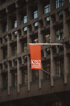 Close-up of King's College London flag on a modern architectural building facade.