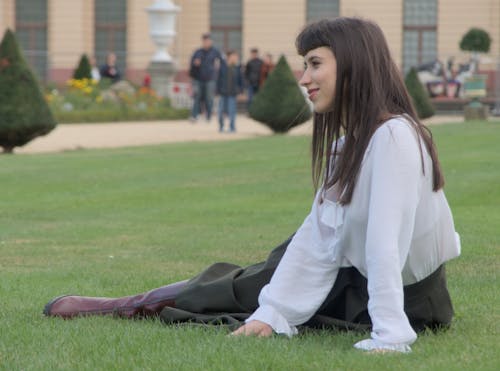 Free Young Elegant Woman Sitting on the Grass in the Garden Stock Photo