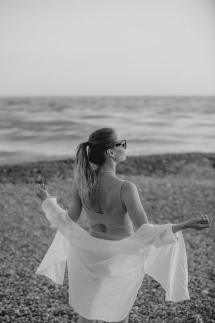 Woman in swimsuit enjoying a serene moment by the beach, captured in black and white.