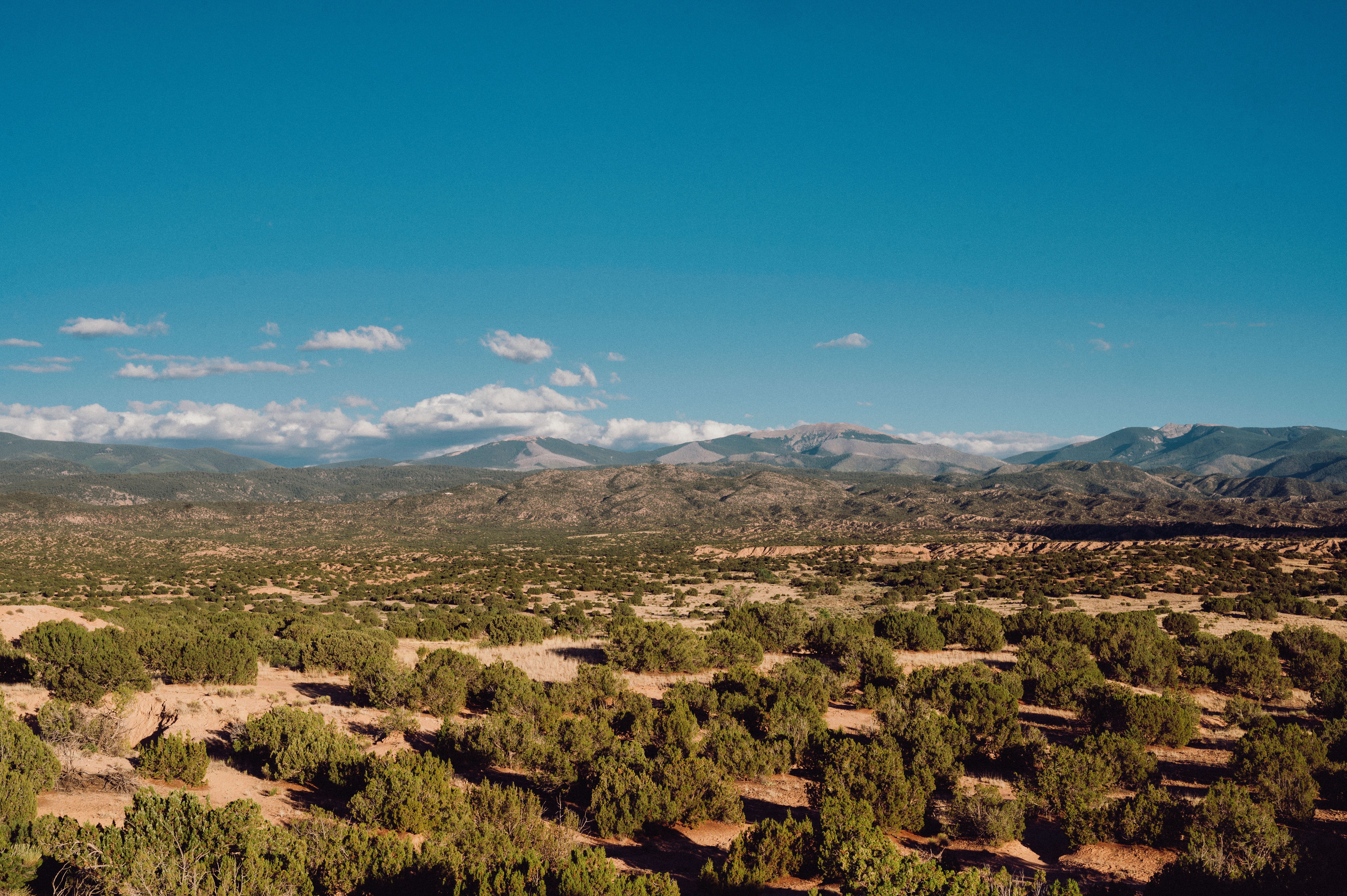 Beautiful mountain range over a desert landscape with greenery under a clear blue sky.