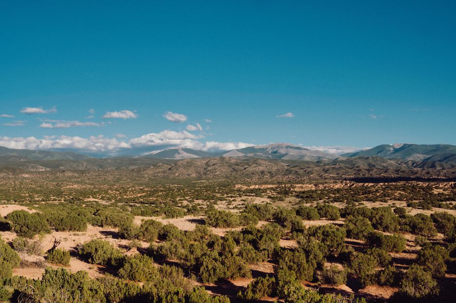 Beautiful mountain range over a desert landscape with greenery under a clear blue sky.