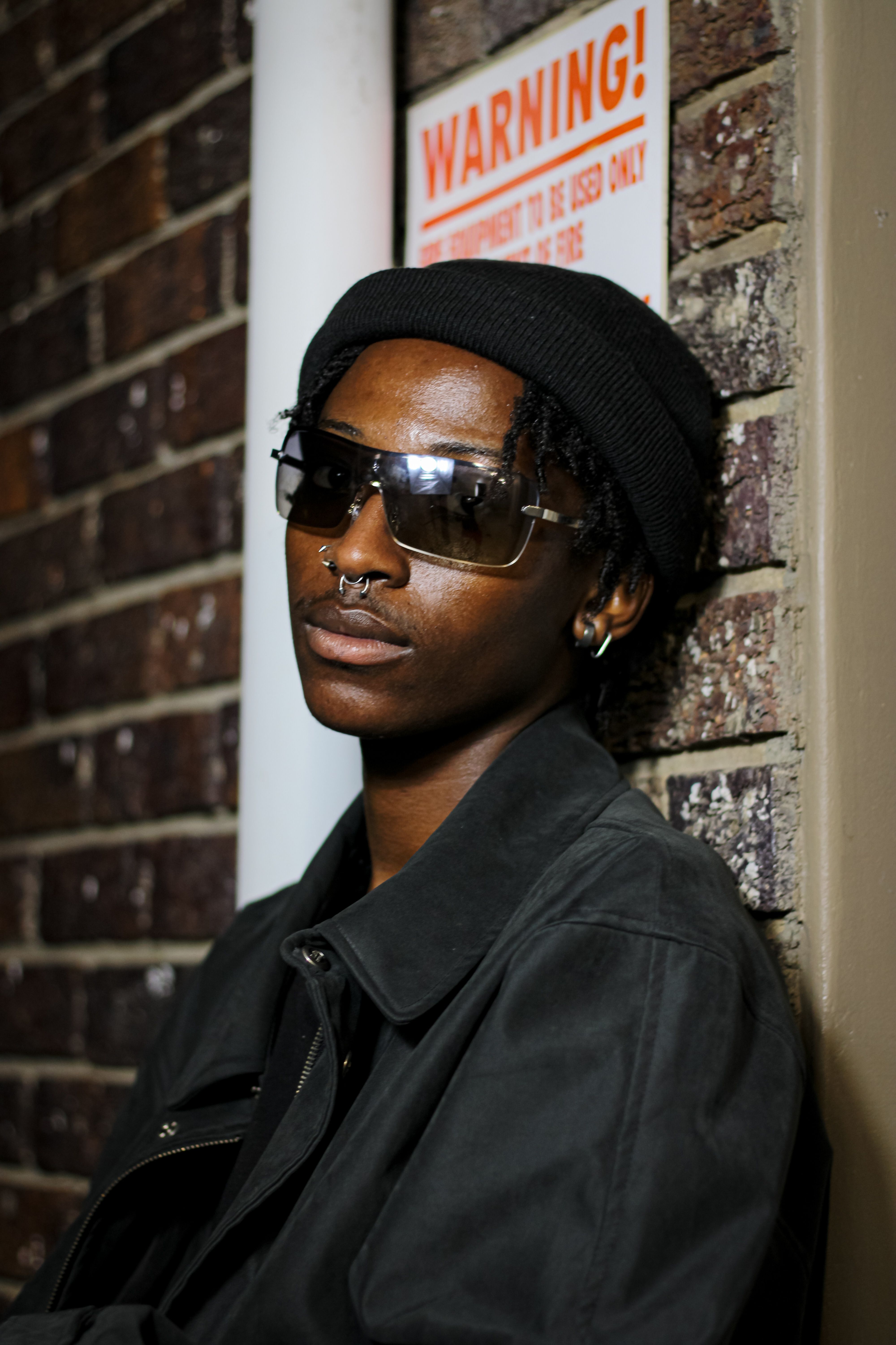 Young Man in a Trendy Outfit and Sunglasses Standing against the Wall ...