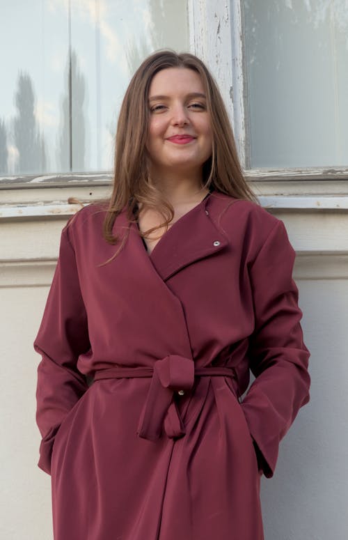 Smiling Woman Wearing a Satin Burgundy Coat Tied with a Belt