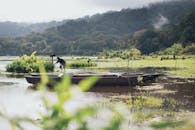 远处雾蒙蒙的山丘上，宁静的湖景与船和人相映成趣