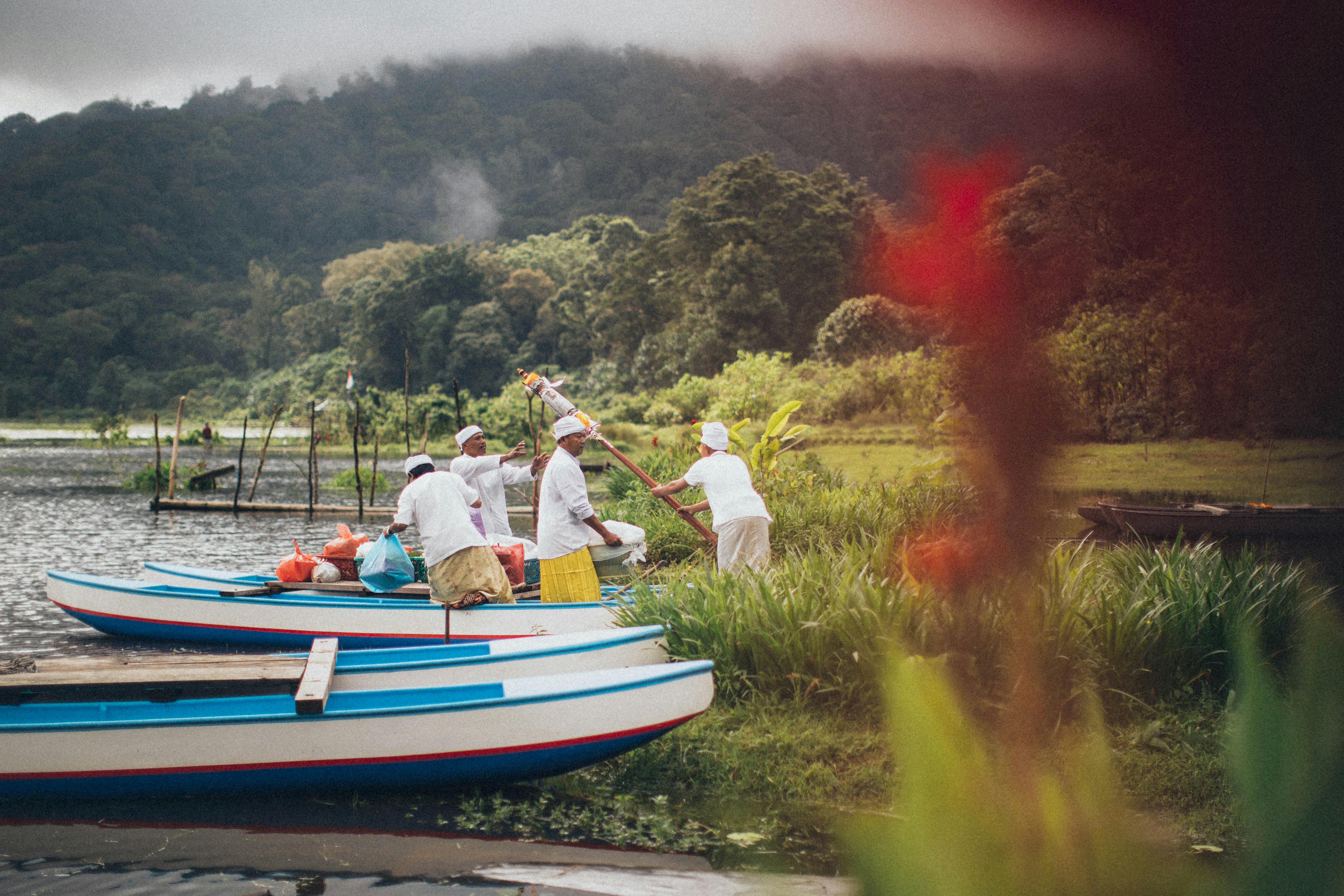 在郁郁葱葱、风景秀丽的湖畔，身着传统服装的渔民正划着独木舟