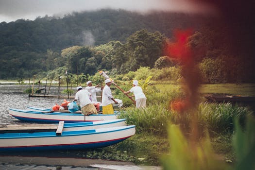 在郁郁葱葱、风景秀丽的湖畔，身着传统服装的渔民正划着独木舟