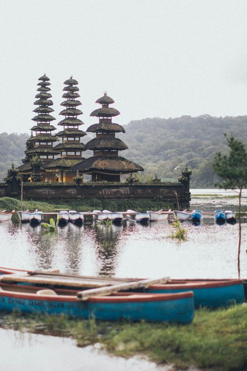Free Scenic view of a traditional Balinese temple by a tranquil lake, surrounded by nature. Stock Photo