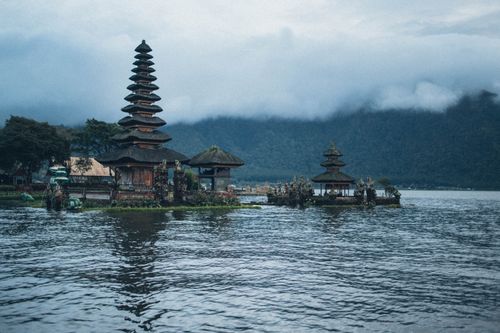 Free A serene view of Ulun Danu Beratan Temple on Lake Bratan, Bali, surrounded by misty mountains and calm waters. Stock Photo
