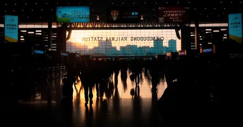 Free Evening silhouettes of passengers at Chengdong Railway Station with city skyline views. Stock Photo