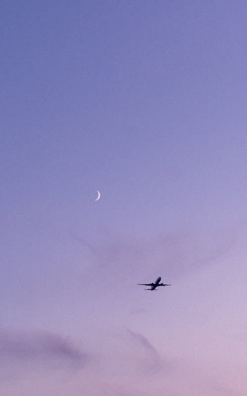 Crescent and Airplane on Clear Sky at Dusk