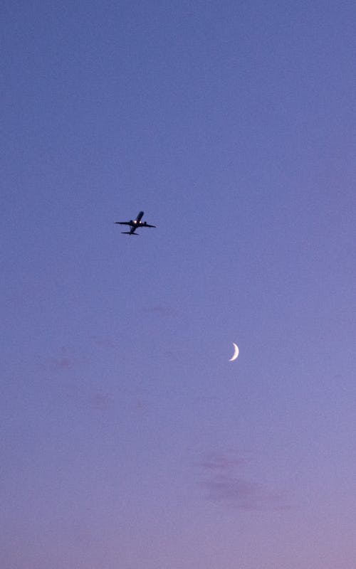 Airplane and Crescent on Clear Sky at Dusk
