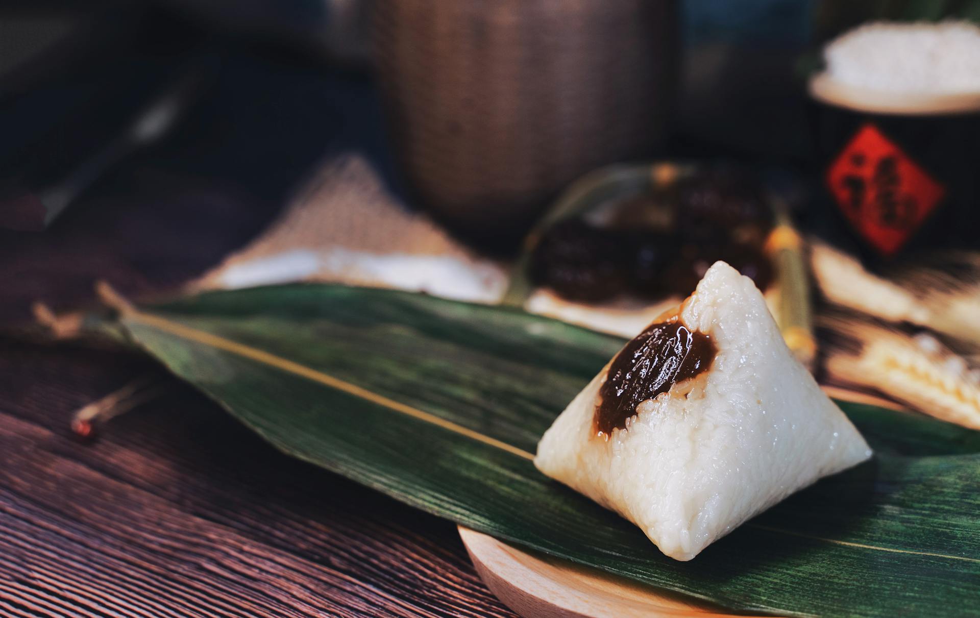 Close-up of traditional zongzi rice dumpling wrapped in leaf, showcasing its sticky texture and rich filling.