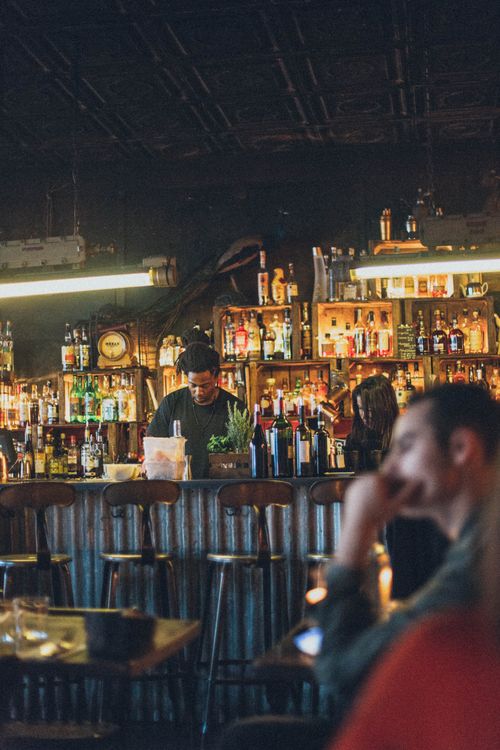 Free Atmospheric bar scene with diverse patrons enjoying drinks and lively ambiance. Stock Photo