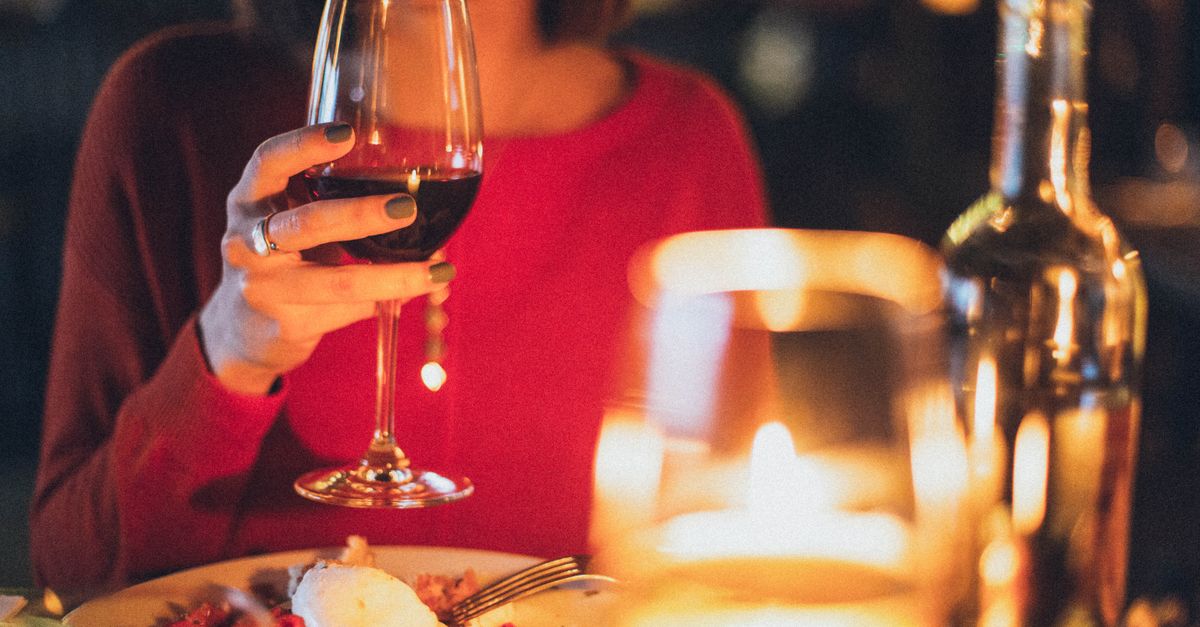 Rüyada Çağatay Ulusoy ile Yemek Yemek - Rüya Tabiri ve Anlamı - A woman enjoying red wine at a romantic candlelit dinner, perfect for celebrations.