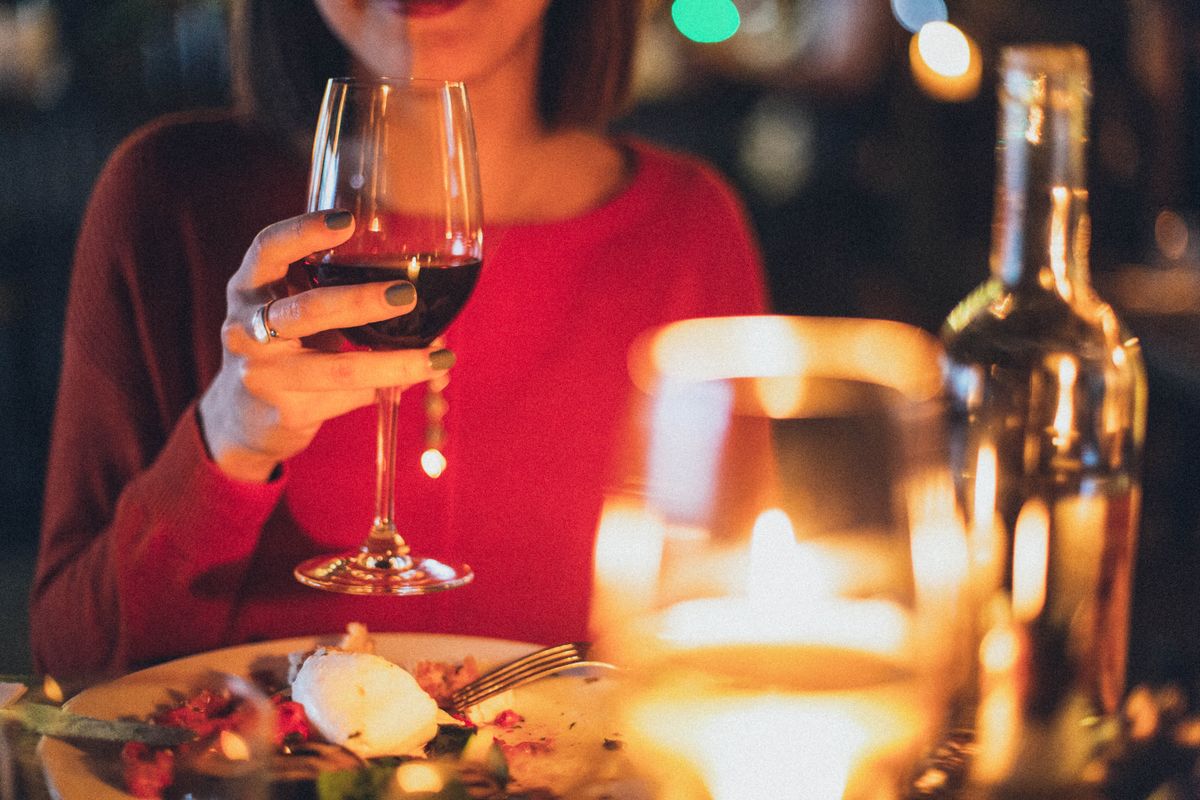 Bad Breath After Alcohol: Why It Lasts Long After You Stop Drinking 1 Woman with red wine at a candlelit dinner, the night before hangover breath that will not go away