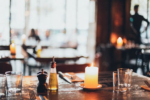 White Candle Beside Two Clear Drinking Glasses