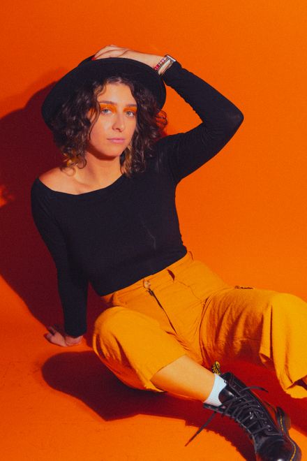 Model in a black top and amber trousers against an orange studio backdrop — Earnest Joseph Odom on Pexels