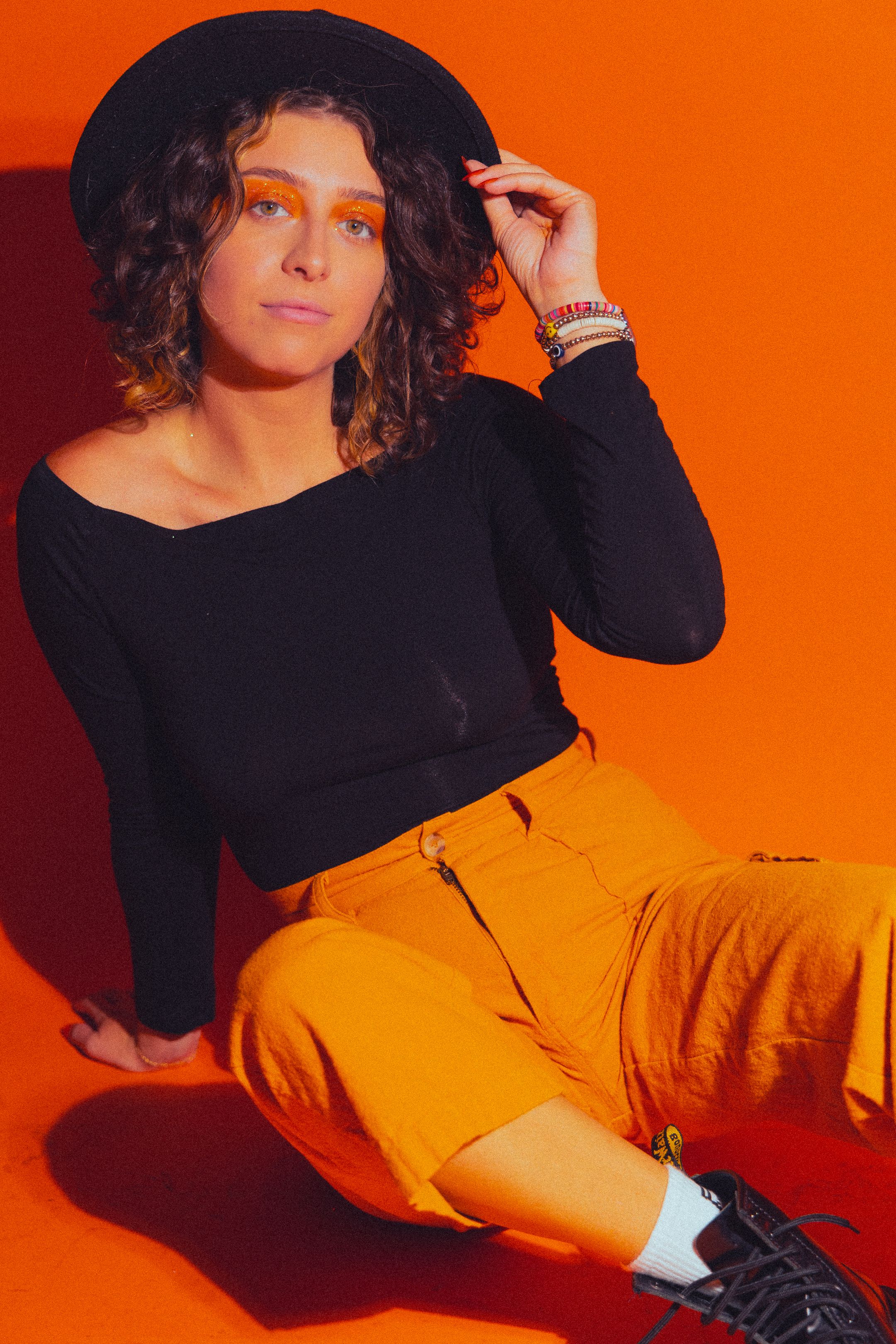 Woman in Hat Sitting on Orange Background · Free Stock Photo