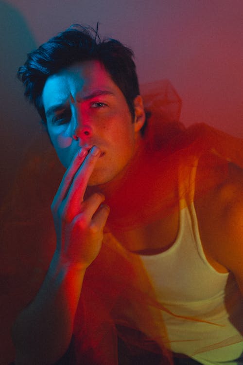 Studio Shot of a Young Man Wearing a White Tank Top and a Tulle Scarf 