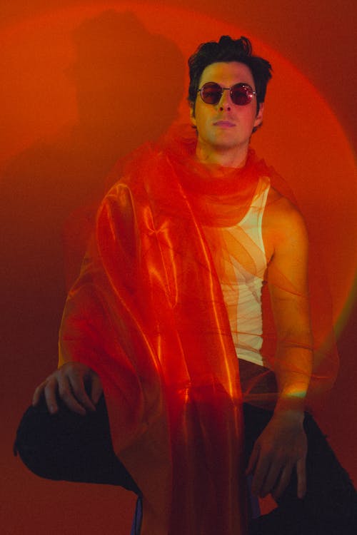 Young Man in a White Tank Top, Tulle Scarf and Sunglasses Posing in Studio 