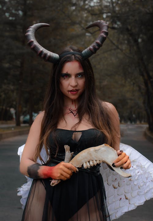 Woman Wearing a Devil Costume Holding a Bone in Her Hand