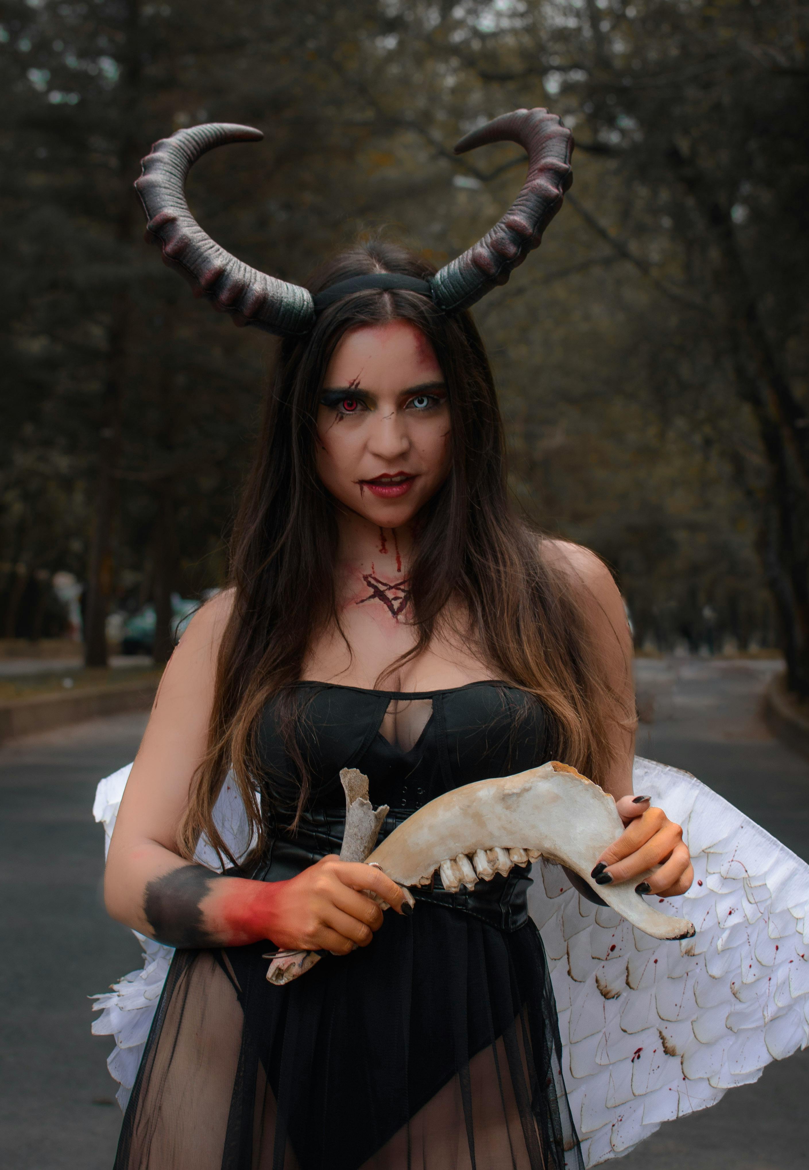 grátis Mulher Vestindo Uma Fantasia De Diabo Segurando Um Osso Na Mão Foto profissional
