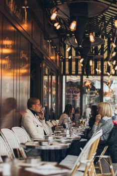 Des adultes savourent une conversation et des boissons dans un cadre de café extérieur élégant.