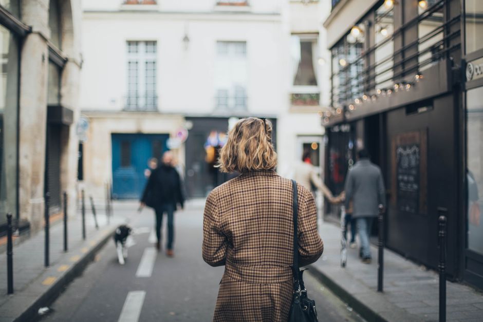 Back view of a woman walking along a quaint city street, capturing the essence of urban life.