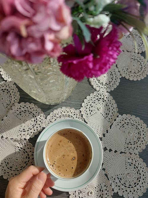 Person Holding a Cup of Coffee on the Table