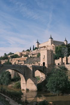 Majestic view of Alcazar with Puente de Alcantara over Tagus River in Toledo, Spain.