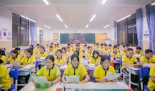 Teenagers in Yellow Polo Shirts Studying at Desks in a Class Room