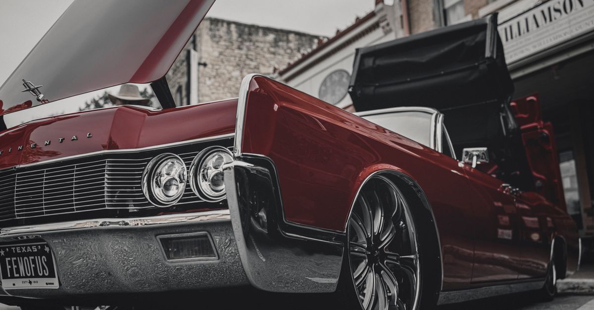 A sleek red Continental car with an open hood captured in urban Georgetown, Texas.