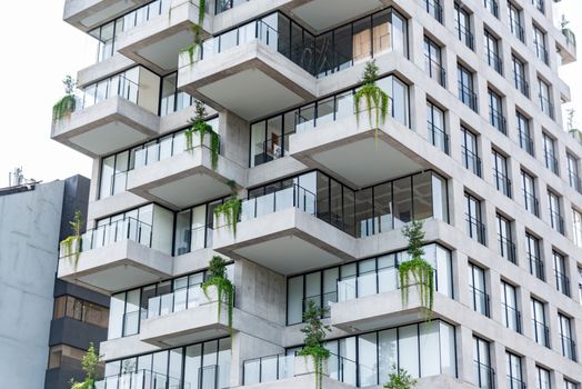 Contemporary residential building featuring geometric design and lush balconies with green plants.