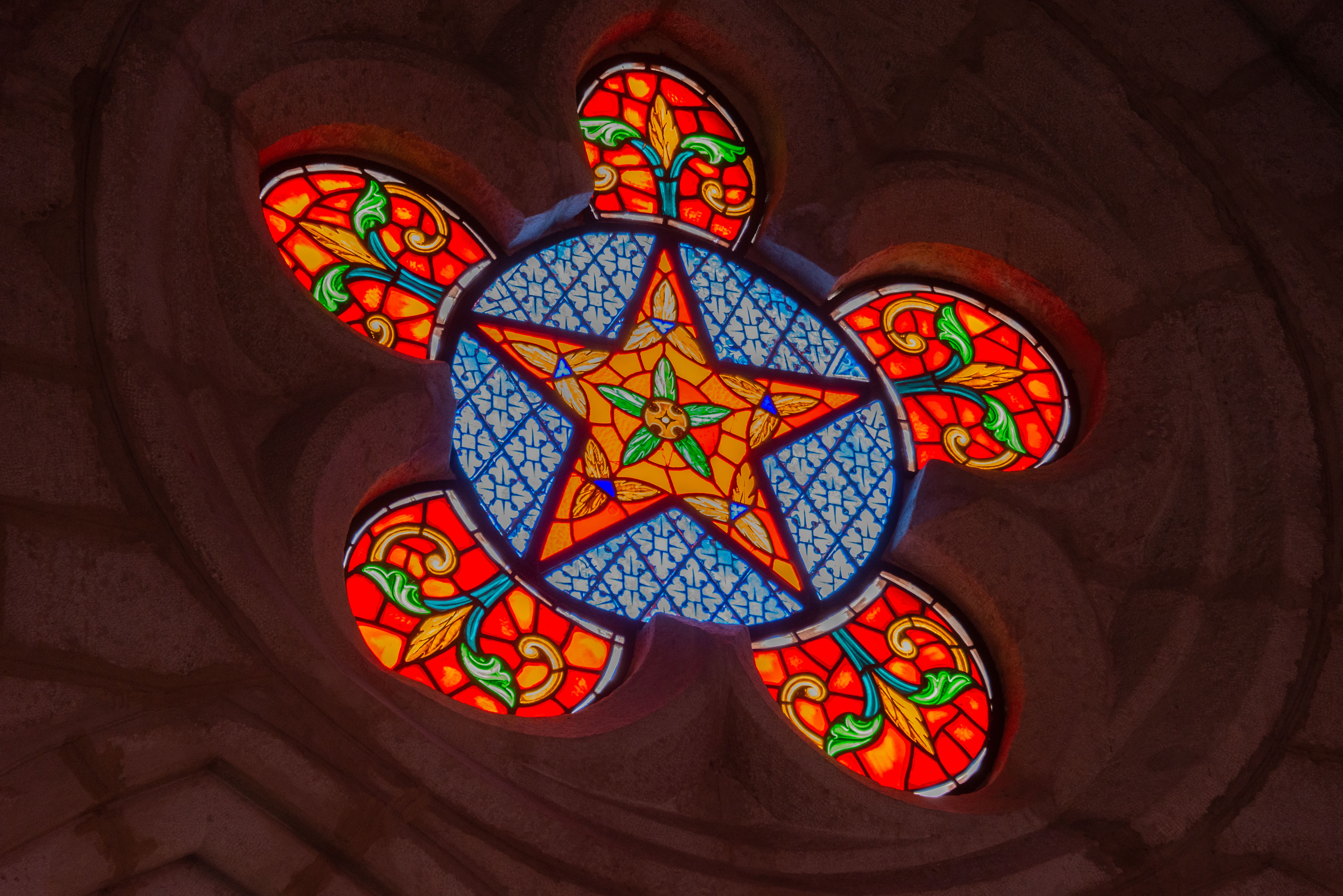 A beautiful and colorful stained glass window featuring a star design in a church setting
